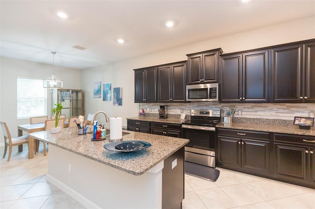 kitchen with sink, stainless steel appliances, a kitchen island with sink, and backsplash