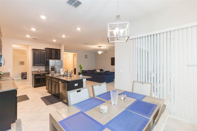 dining room with sink, light tile patterned flooring, and ceiling fan with notable chandelier