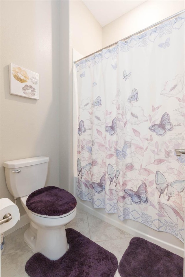 bathroom with shower / bathtub combination with curtain, tile patterned flooring, and toilet