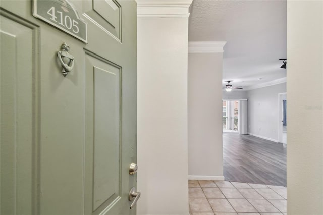 tiled entryway featuring ceiling fan and ornamental molding