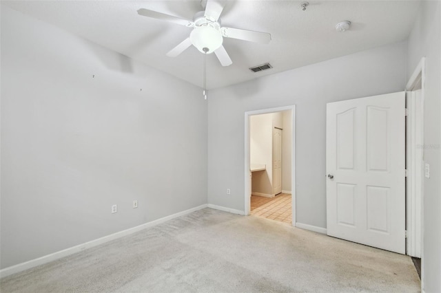 unfurnished bedroom with ceiling fan, light carpet, and connected bathroom