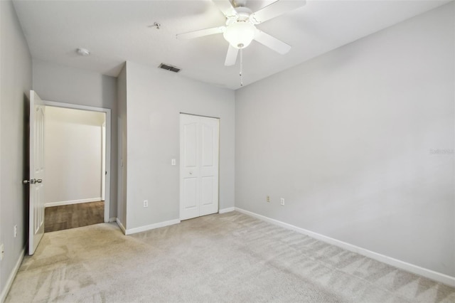 unfurnished bedroom featuring ceiling fan, light colored carpet, and a closet