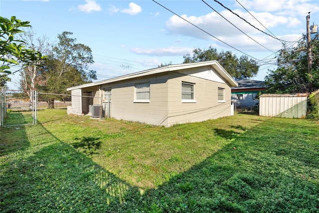 back of house featuring a yard, central AC unit, and a storage unit