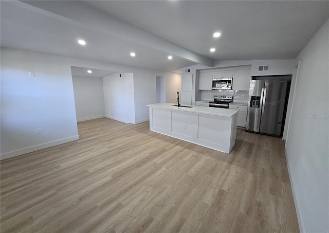 kitchen featuring sink, a kitchen island with sink, stainless steel appliances, light hardwood / wood-style floors, and decorative backsplash