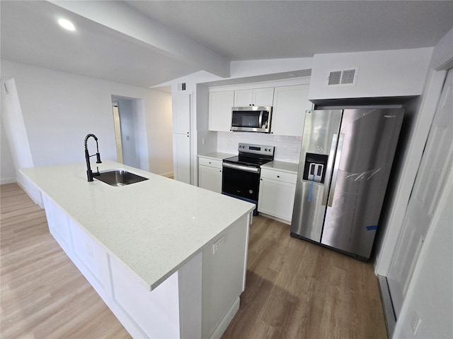 kitchen featuring a kitchen island with sink, white cabinets, and appliances with stainless steel finishes