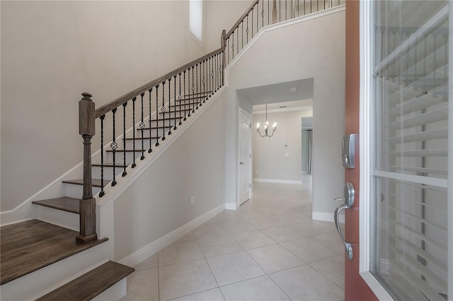 stairs with tile patterned floors, a high ceiling, and a chandelier