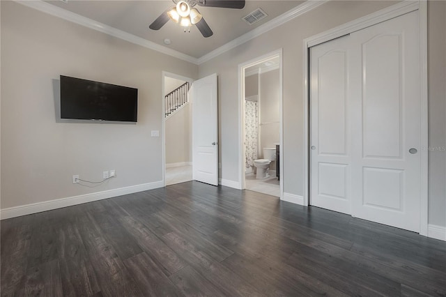 unfurnished bedroom featuring ceiling fan, dark hardwood / wood-style floors, ornamental molding, connected bathroom, and a closet