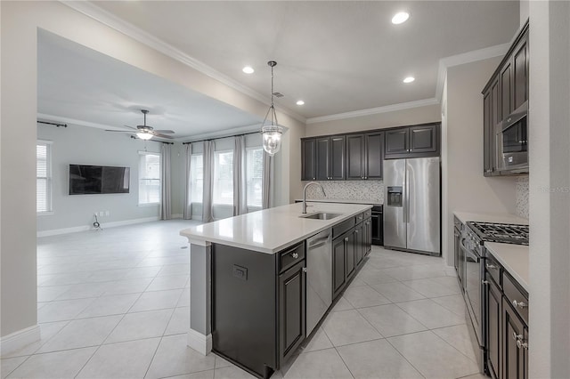 kitchen featuring pendant lighting, a kitchen island with sink, sink, ornamental molding, and stainless steel appliances