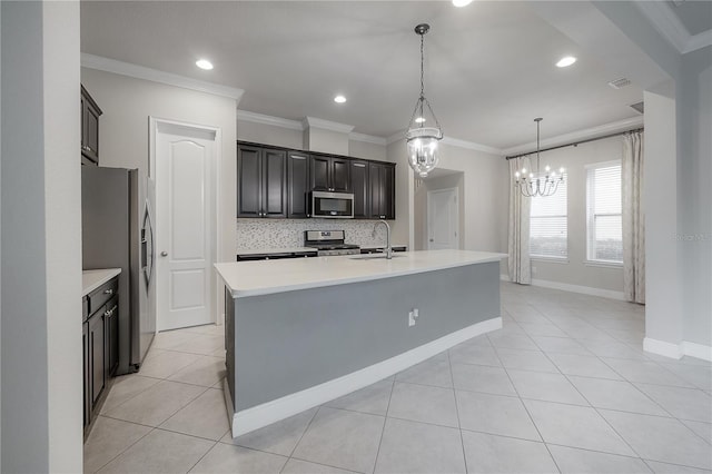 kitchen featuring sink, stainless steel appliances, backsplash, an island with sink, and decorative light fixtures