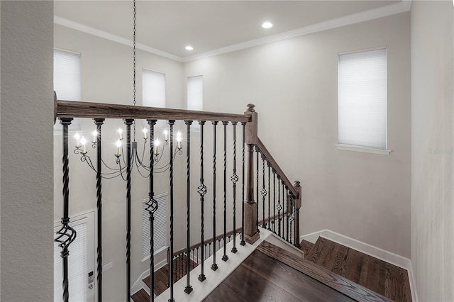 stairs with a chandelier, wood-type flooring, and ornamental molding