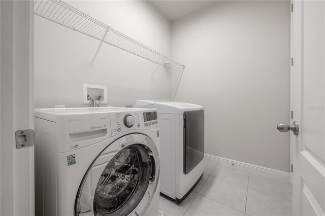 clothes washing area with light tile patterned floors and independent washer and dryer