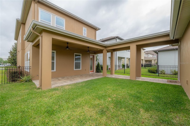 rear view of property with a lawn, ceiling fan, and a patio