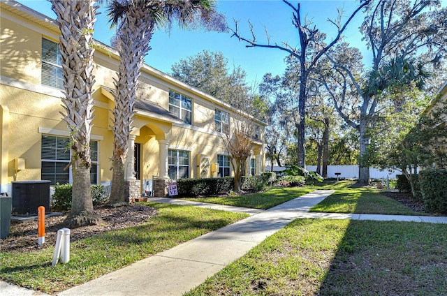 view of front of house with central AC unit and a front lawn