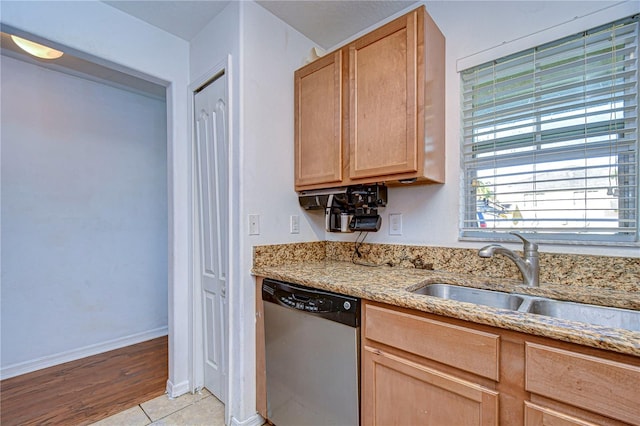 kitchen featuring stainless steel dishwasher, light tile patterned flooring, light stone countertops, and sink