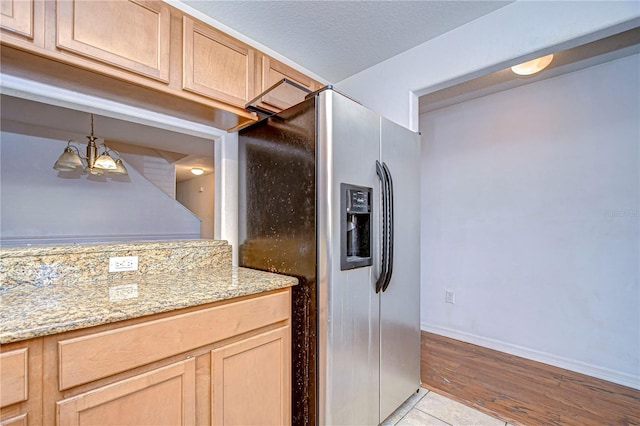 kitchen featuring decorative light fixtures, stainless steel fridge, light tile patterned floors, light brown cabinetry, and a notable chandelier