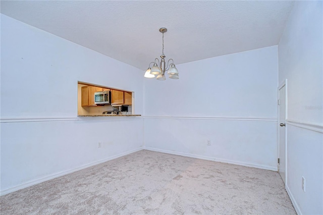 empty room with a notable chandelier and light carpet