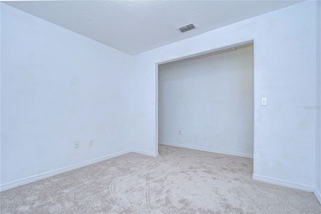 empty room featuring light carpet and a textured ceiling