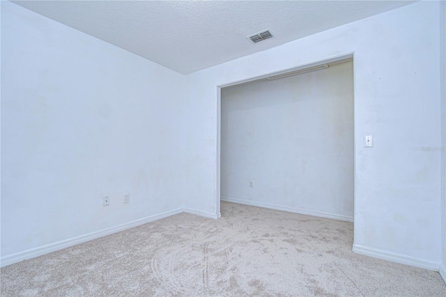 carpeted empty room with a textured ceiling