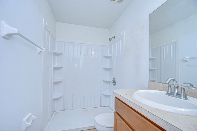 bathroom featuring a shower, vanity, and toilet