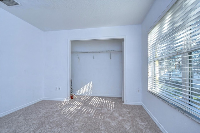 unfurnished bedroom with multiple windows, a closet, and carpet