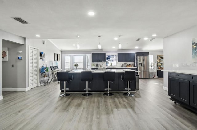 kitchen featuring a kitchen island, a kitchen bar, stainless steel fridge with ice dispenser, and hanging light fixtures