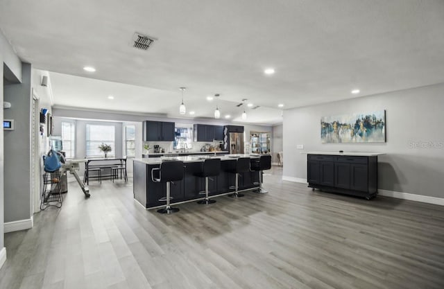 kitchen with a center island, backsplash, light wood-type flooring, a kitchen bar, and stainless steel fridge with ice dispenser