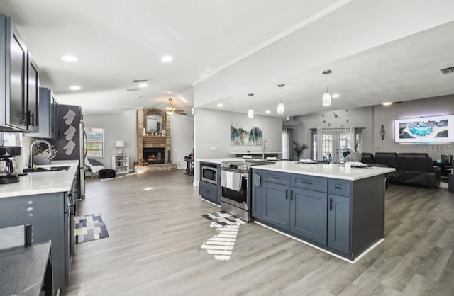 kitchen with a kitchen island with sink, pendant lighting, hardwood / wood-style flooring, and appliances with stainless steel finishes