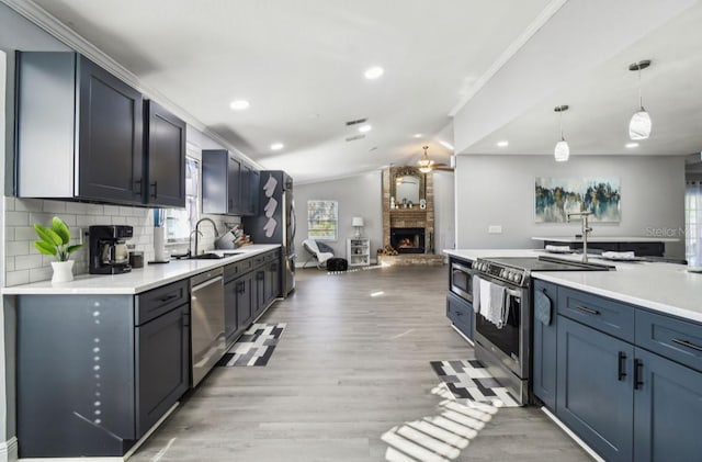 kitchen with sink, backsplash, pendant lighting, appliances with stainless steel finishes, and light wood-type flooring