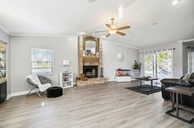 living room featuring ceiling fan, a fireplace, light hardwood / wood-style floors, and ornamental molding