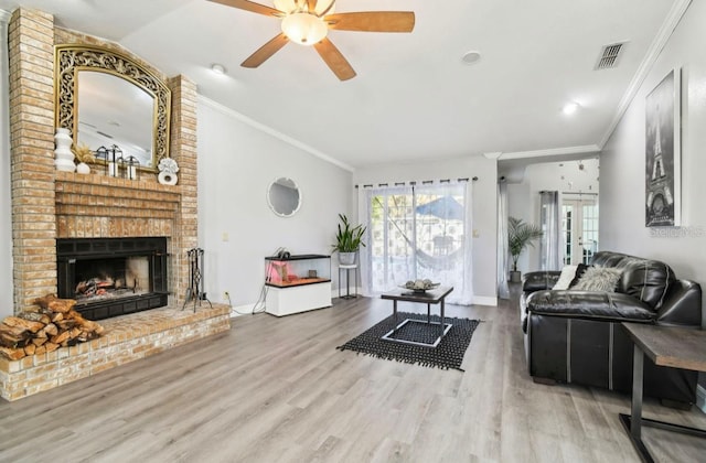 living room featuring ceiling fan, crown molding, wood-type flooring, and a brick fireplace