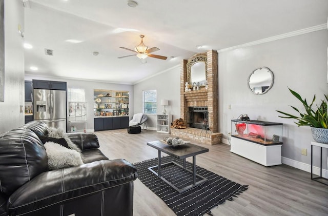 living room with hardwood / wood-style floors, a fireplace, crown molding, and vaulted ceiling