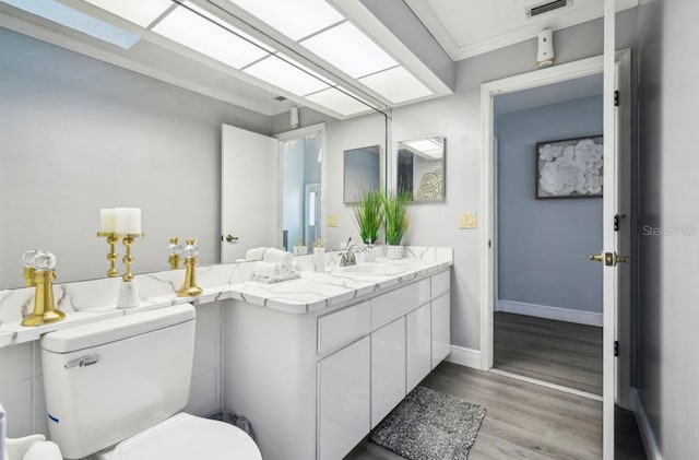 bathroom with vanity, toilet, wood-type flooring, and ornamental molding