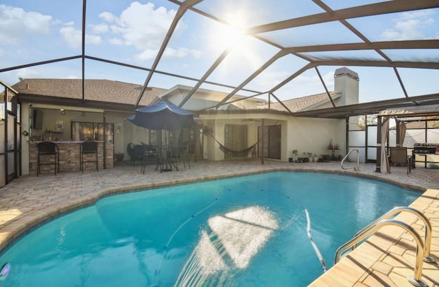 view of swimming pool featuring exterior bar, a patio, and glass enclosure