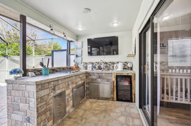 view of patio / terrace featuring glass enclosure, sink, beverage cooler, and an outdoor kitchen