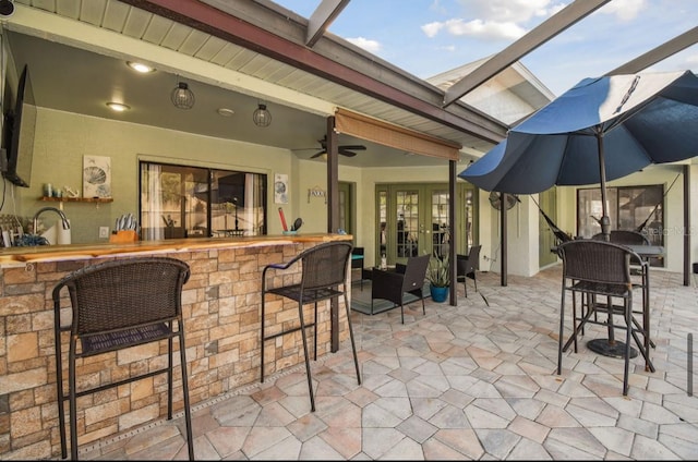 view of patio / terrace with french doors, glass enclosure, ceiling fan, and a wet bar