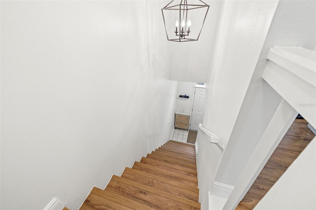 stairs featuring hardwood / wood-style floors and a chandelier