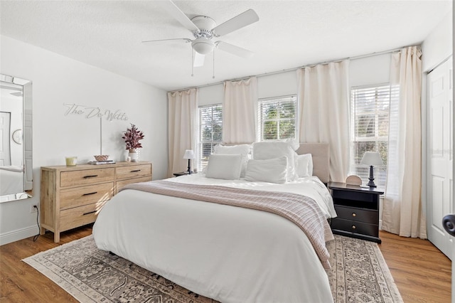 bedroom with ceiling fan, wood-type flooring, a textured ceiling, and a closet