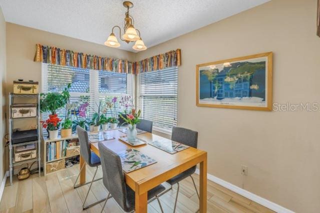 dining room with hardwood / wood-style flooring, a textured ceiling, and a chandelier