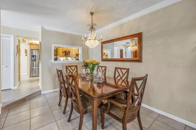 tiled dining space with an inviting chandelier and ornamental molding