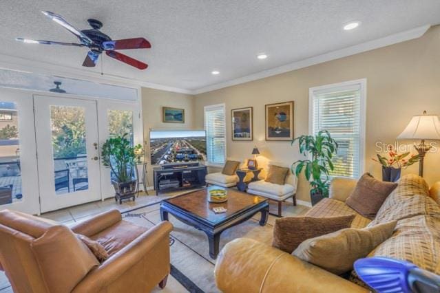 tiled living room with ceiling fan, ornamental molding, a textured ceiling, and french doors