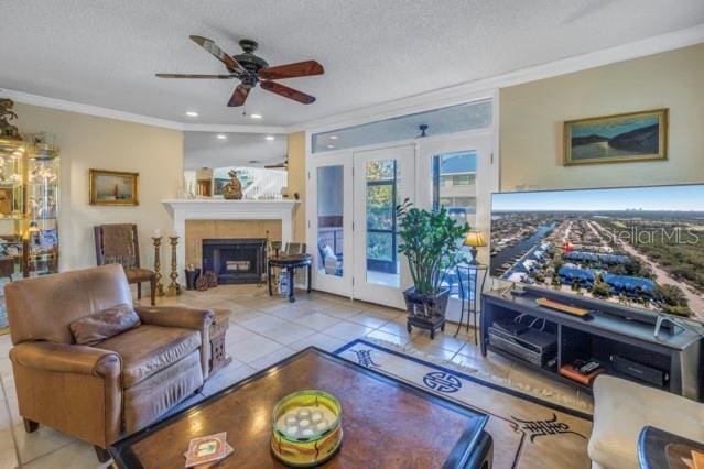 living room featuring light tile patterned floors, a textured ceiling, ceiling fan, and crown molding