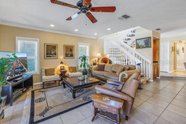 living room featuring a textured ceiling, ceiling fan, ornamental molding, and light tile patterned flooring