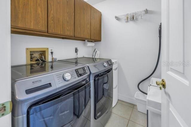 laundry room with separate washer and dryer, light tile patterned floors, and cabinets