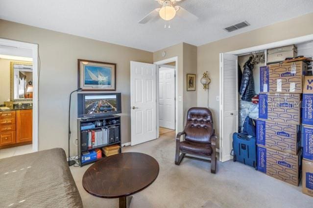 living area featuring light colored carpet and ceiling fan