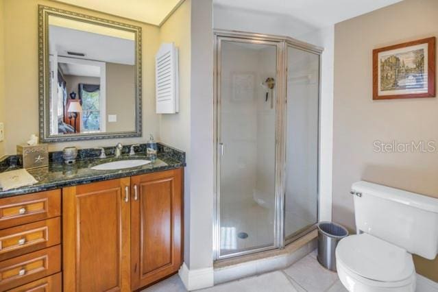 bathroom with tile patterned flooring, vanity, an enclosed shower, and toilet