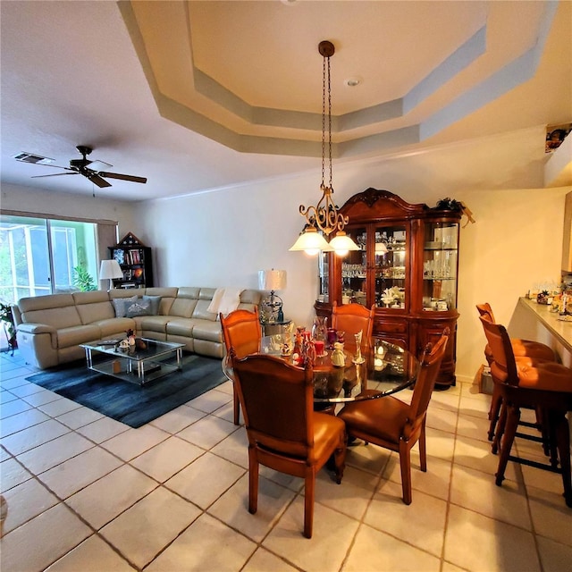 tiled dining space with a raised ceiling and ceiling fan with notable chandelier