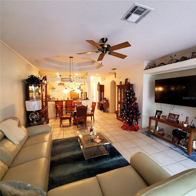 tiled living room featuring a raised ceiling, ceiling fan, and a textured ceiling