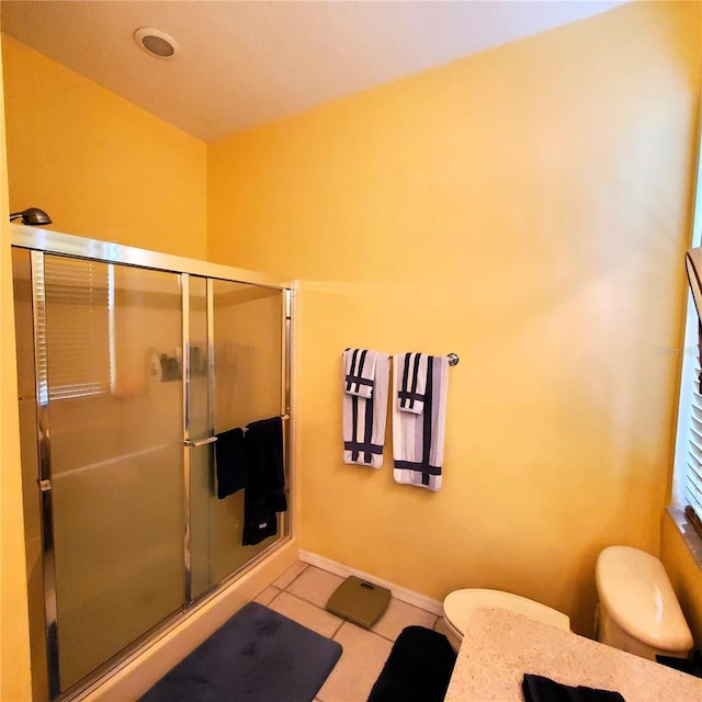 bathroom featuring toilet, tile patterned floors, and a shower with shower door