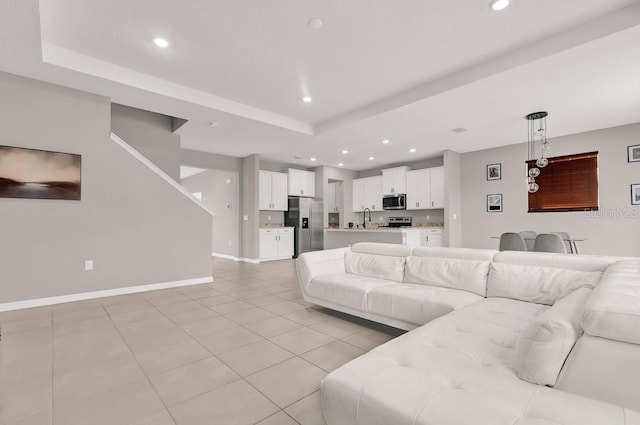 living room with a raised ceiling, light tile patterned floors, and sink