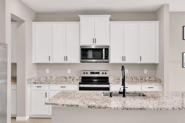 kitchen featuring white cabinetry, sink, light stone counters, and appliances with stainless steel finishes